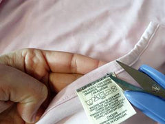 Demonstrating how the label can be easily cut and removed from clothing