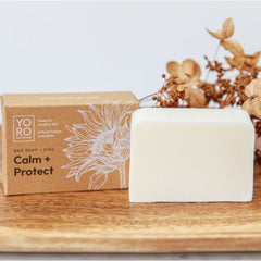 calm protect zinc cleansing bar and packaging on wood board soothes redness and irritation for eczema-prone and sensitive skin fragrance-free 2% zinc oxide